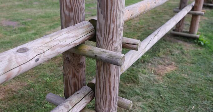 new wooden fence made of logs and roundwood in rural areas, primitive fencing against large animals in rural areas during the summer season, cloudy weather