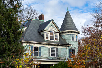 Charming weathered home with slate roof and turret framed by autumn branches in Brighton, Boston, Massachusetts, USA  © Baharlou