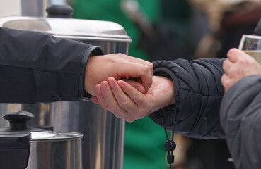 Close-up of a cash transaction at hot drinks stall at Naplavka market, vendor returns coins to customer, capturing the authentic moment of buying, selling, and paying with cash in busy Prague market.