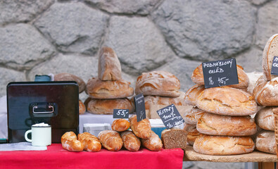 Bakery stall at Naplavka farmers market with stacks of fresh artisan bread, crispy golden crusts and rustic loaves, a popular Saturday food destination for locals in Prague.
