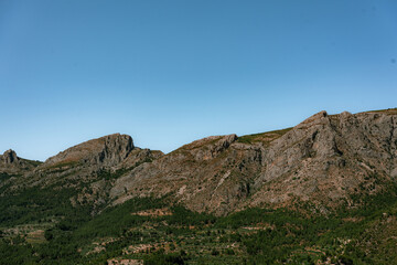 Fototapeta premium Stunning rocky mountain range under a clear blue sky in South Spain, ideal for nature, travel, and adventure themes. Perfect for backgrounds, blogs, or travel inspiration.