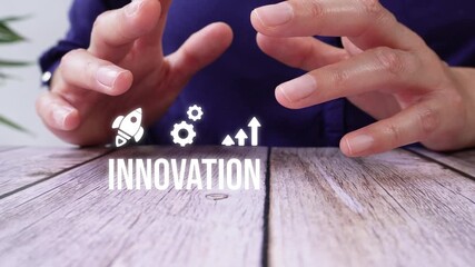 Close-up of a pair of hands on a table, shielding an innovation animation with rocket, gear, and ascending arrow icons.