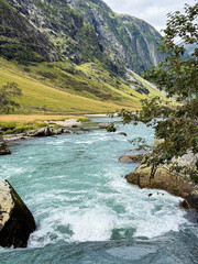 Rushing turquoise river water flowing through sunnfjord valley