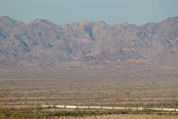 Fototapeta premium Train running through town by Imperial sand dunes with mountainous background in Glamis california