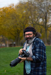 Senior Man Holding Professional Camera Outdoors in a Park