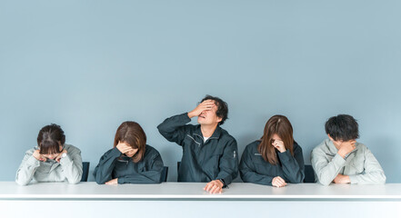 A businessman and woman in work clothes holding their heads