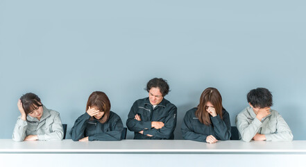 A businessman and woman in work clothes holding their heads
