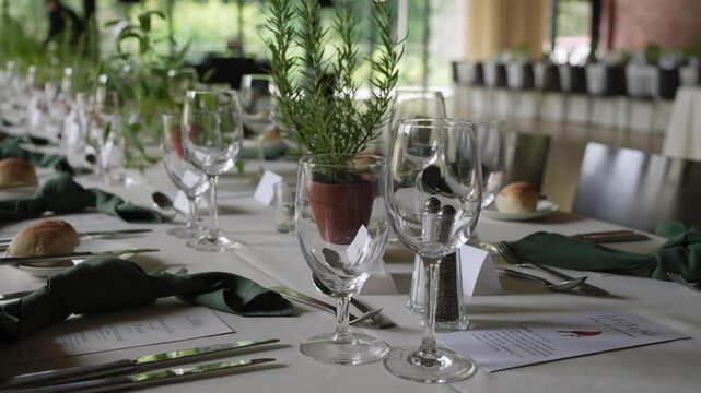 Table Set With Potted Herbs And Bread Rolls, White Linen, Green Napkins, Crystal Glassware, Silver Cutlery, Handwritten Name Cards, Soft