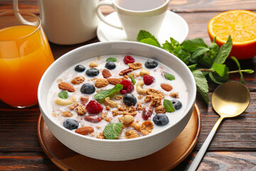 Healthy breakfast. Oatmeal with nuts, berries and milk in bowl on wooden table, closeup
