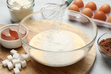 Making dough. Sieving flour into bowl and different ingredients at grey table, closeup