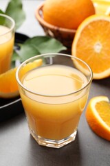 Fresh orange juice and fruits on grey table, closeup