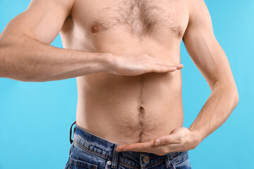 Man with healthy stomach on light blue background, closeup