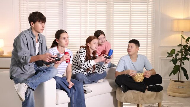 Teenagers playing video game on sofa at home