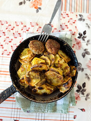 Homemade fried potatoes with meatballs in pan