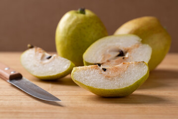 Sliced pear fruit on cutting wooden board with kitchen knife