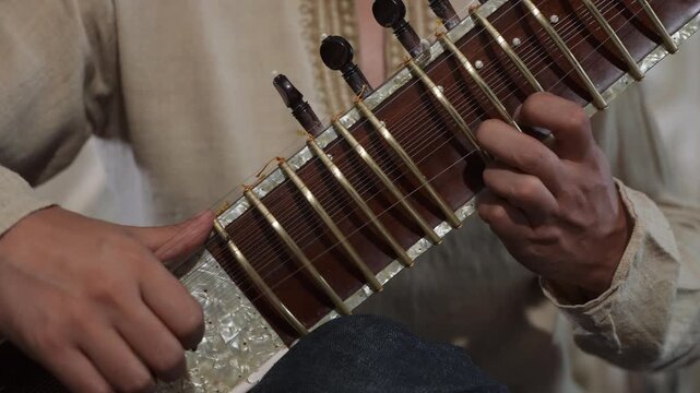 CloseUp Sitar Hands Plucking Strings In Intimate Home Studio, Session Musician Practicing Raga Phrases On Ornate Instrument, Warm Natural