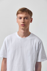 Young man in white tshirt stands against a neutral background, showcasing casual minimalist fashion...