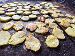Potato slices drying on rustic stove surface