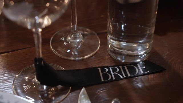Bride Placecard Beside Wine Glass On Wooden Table, Soft Candlelight And Cutlery In Shallow Focus, Intimate Elegant Reception Detail