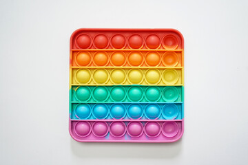 Colorful rainbow pop-it fidget toy with rows of bubbles on a clean white background, viewed from directly above.