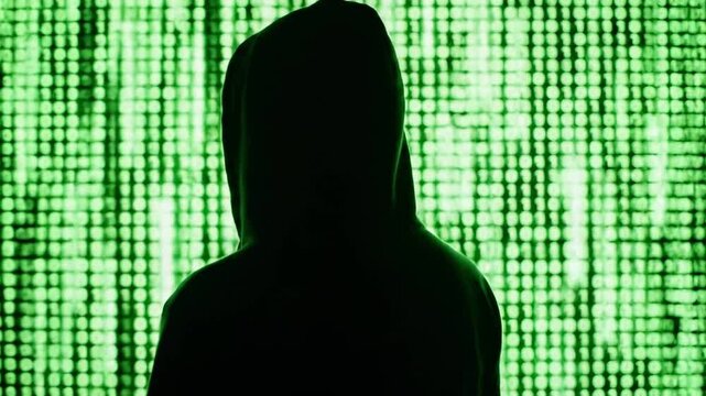 A hooded silhouette faces a neon-green matrix wall of binary, hinting at covert cyber hacking. at dusk