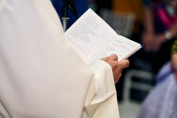 The hands of an elderly priest, holding and reading the Holy Bible, to a couple in a marriage, reveal its symbolism, words, illustrations, details, which he holds in his hands with great devotion.