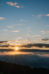 A breathtaking sunrise above the clouds, with rays of sunlight piercing through the sky, creating a serene and picturesque landscape.