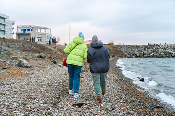 Two Russian friends aged 50 and 60 walk along the cold spring shore, talking and sharing calm...