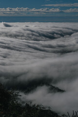 A breathtaking view of rolling clouds blanketing a mountainous landscape, creating a serene and ethereal atmosphere.