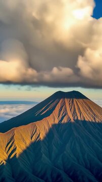Majestic volcanic peak bathed in the warm glow of sunrise, with dramatic clouds swirling above, casting long shadows across the rugged slopes of this breathtaking natural landscape