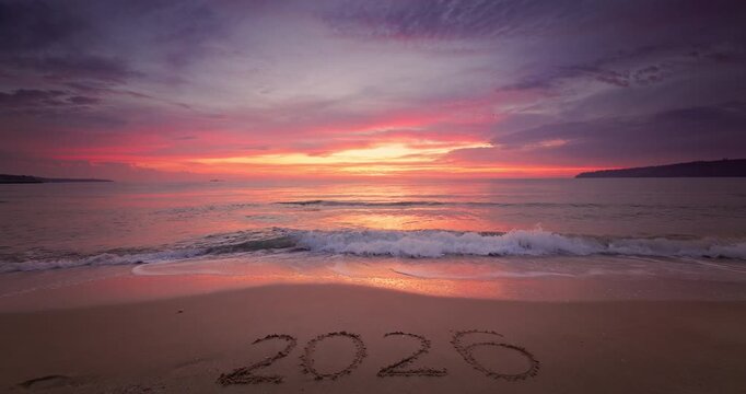 Sunset on the beach shore and sea horizon and text Happy New Year 2026 on the sand