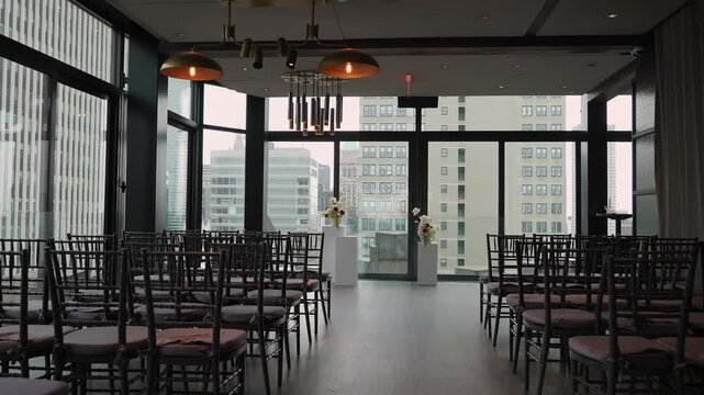 Empty Urban Ceremony Space Overlooking Skyline, Modern Chiavari Chairs Aligned Toward Floral Pedestal, FloorToCeiling Windows Framing City