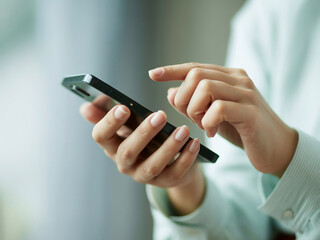 スマホを操作する女性の手元　A close-up of a woman's hands operating a smartphone　Generative AI