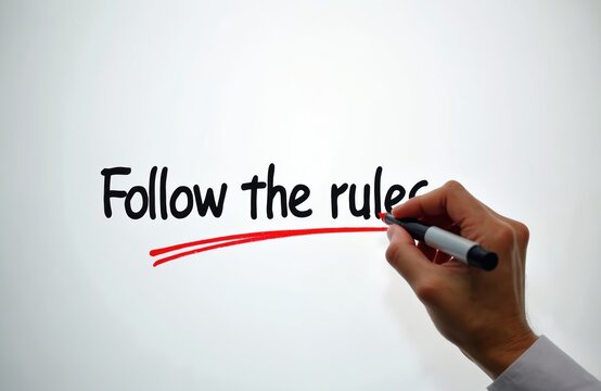 Hand writes follow the rules text with red marker on white board. Human hand underlines important message about compliance. Stick to instructions message.