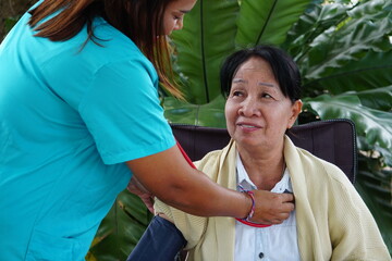 A close-up shows the nurse adjusting the blood pressure cuff while the older woman looks on with a smile.
