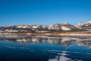 Baikal Lake in winter. Beautiful landscape with mountains reflected in ice of frozen Small Sea