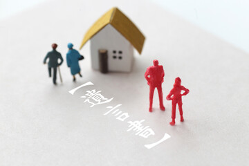 遺産相続のトラブルをミニチュア人形と家と文言で表現した写真