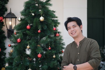 A man stands in front of a Christmas tree, smiling. Crishmas Xmas Holiday background Concept.
