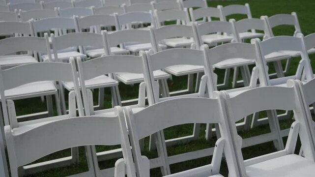 Empty White Folding Chairs On Lawn Arranged In Multiple Rows For Outdoor Wedding Ceremony, Neat Alignment And Repeating Patterns Create Calm