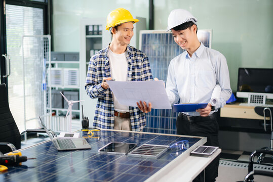 Two Asian engineers collaborate on a solar and wind energy project, discussing innovation