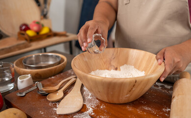 Baking Moments: An individual, deeply immersed in the joy of creating culinary delights, carefully adds a precise measure of ingredients to a bowl.