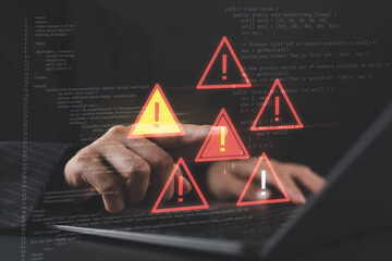 Close-up of a businessperson typing code on a laptop with warning alerts, representing cybersecurity threats, system vulnerabilities, and data breach risks.