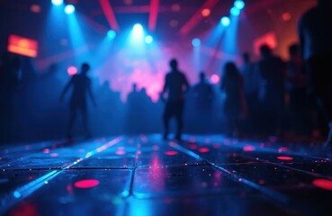 Blurry disco club dance floor with people silhouettes dancing. Neon blue and pink laser lights flash in smoky dark nightclub creating vibrant nightlife atmosphere for partygoers.