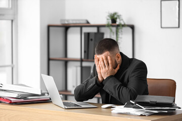 Depressed businessman at desk in office. International Stress Awareness Week