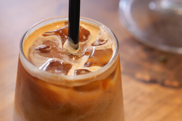 Iced coffee in glass with straw on wooden table