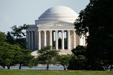 Jefferson Memorial framed by trees on a sunny day in Washington DC, USA, iconic neoclassical landmark. g.