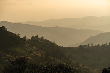 Serene Sunrise Over Rolling Mountains with Layers of Fog and Soft Light Casting Shadows Across the Landscape in a Tranquil Environment