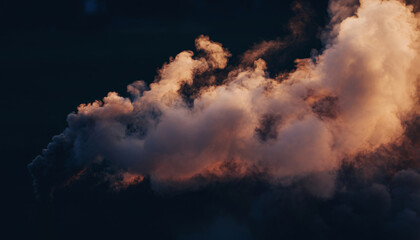 dark clouds with bright edges illuminated by sunlight against a dark sky.