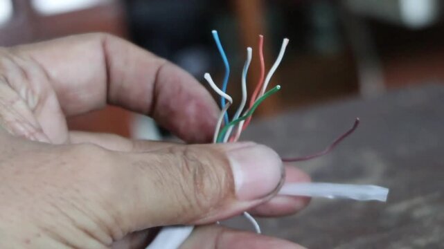 Network technician stripping and splicing local area network cables for internet
