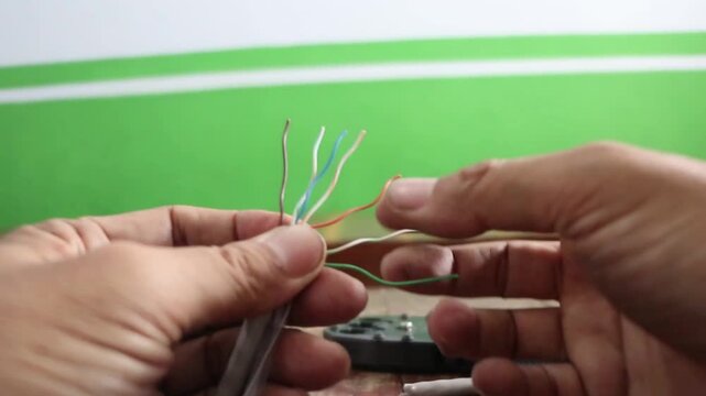 Network technician stripping and splicing local area network cables for internet